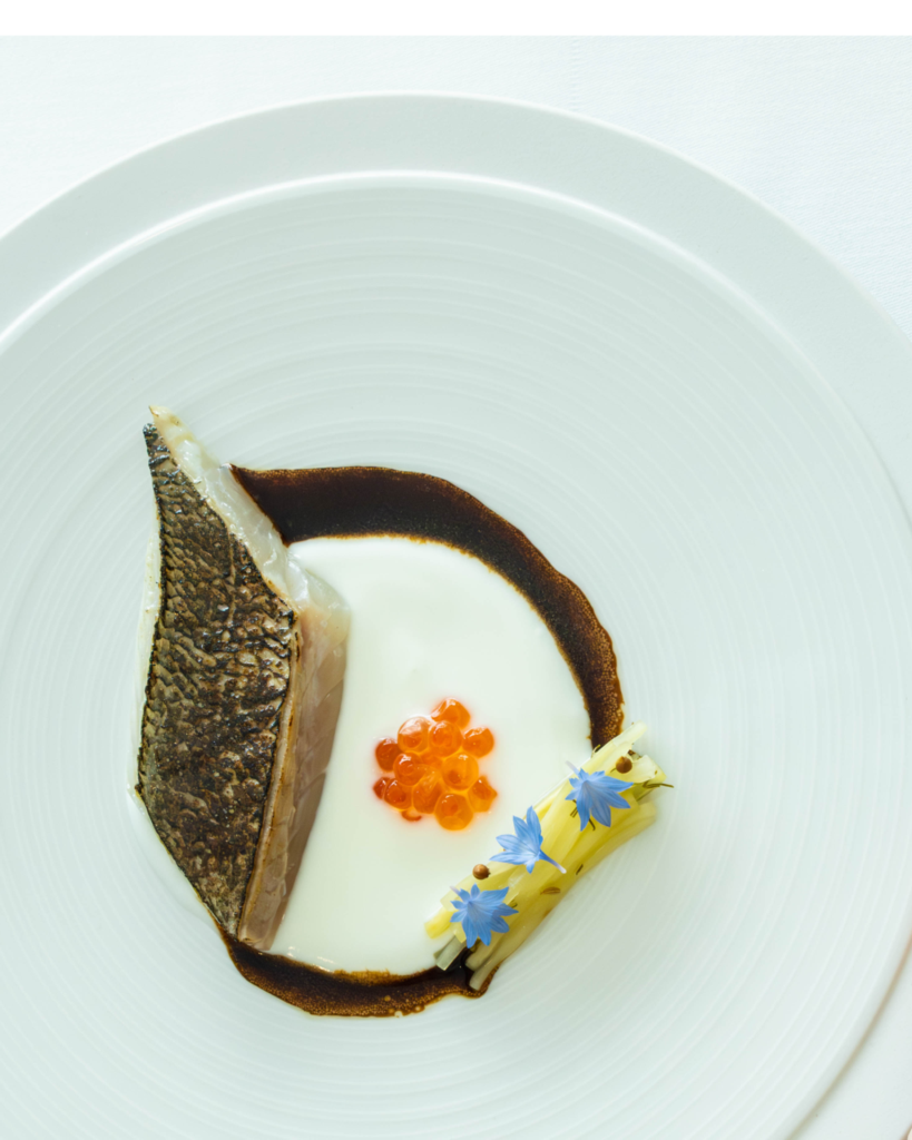 Plate of fish with caviar and decorative sauce in a circle.